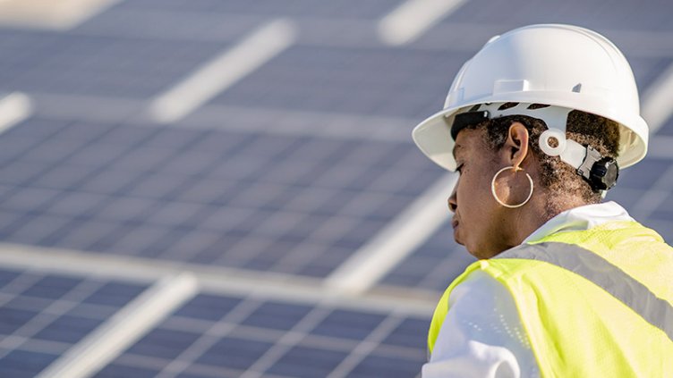 Woman wearing hard hat in front of solar panels
